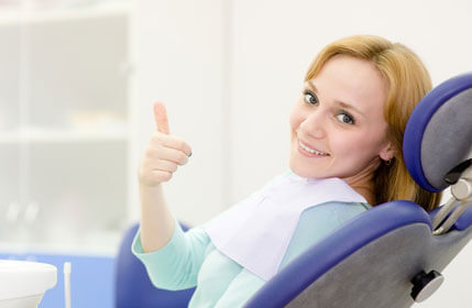 a woman in a dental chair giving a thumbs up